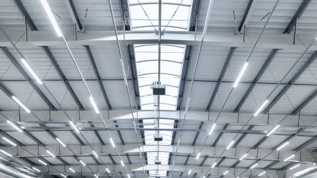 Ceiling of an industrial space featuring LED lights and skylights for illumination.
