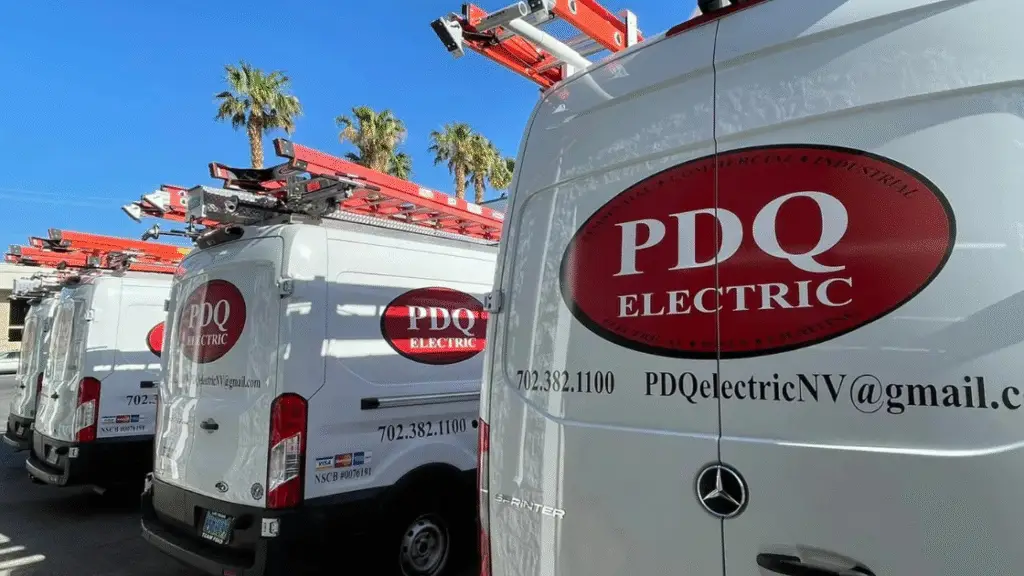 Multiple PDQ Electric service vans lined up, featuring company branding and contact information.
