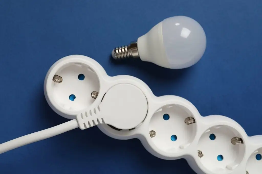 Energy saving bulb and power strip on blue background