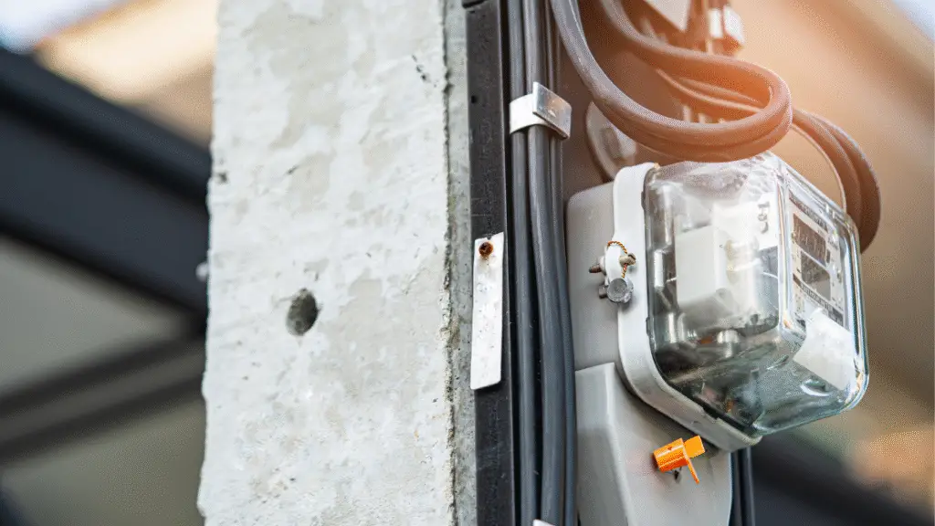 Electric meter attached to a concrete post with electrical cables running alongside it.