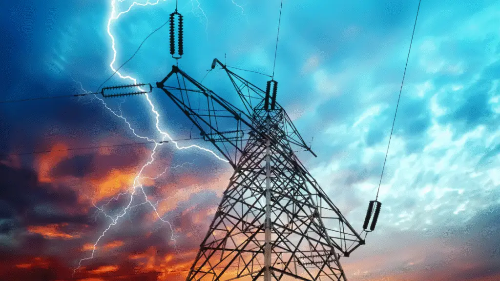 High voltage power line tower against a dramatic sky with lightning strikes in the background.