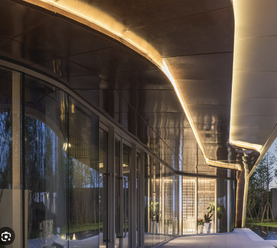 Warm linear LED accent lighting following a curved canopy above commercial storefronts